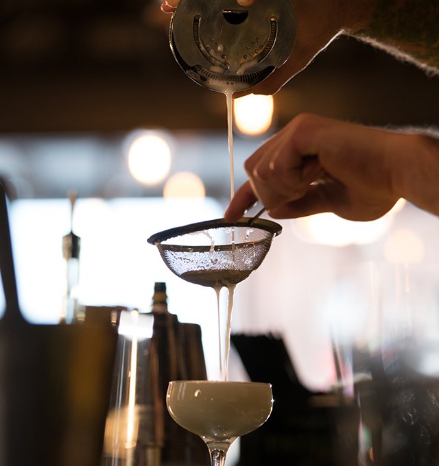 Bartender straining a craft cocktail